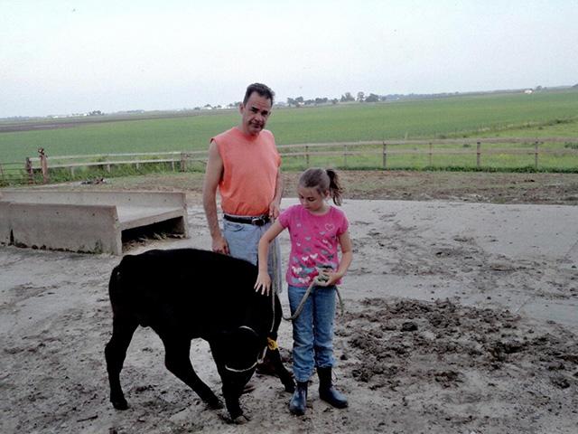 Emma Yerkey with her dad, Tim Yerkey, and a ribbon-winning calf they raised together. The family farms near Geneseo, Illinois. Tim Yerkey died by suicide in 2011. He had been struggling for about a year when spring floods left fields underwater. He had visited the emergency room seeking mental-health help, only to be told there were no beds, Yerkey said. (Photo courtesy of Emma Yerkey) 